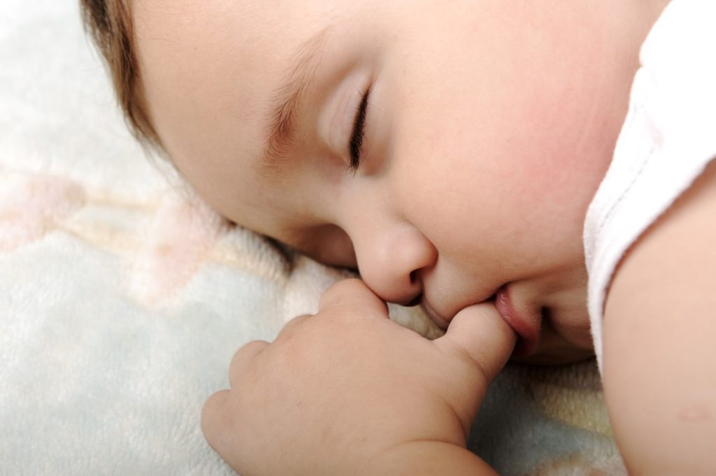Bayi sedang tidur dengan jari di dalam mulut