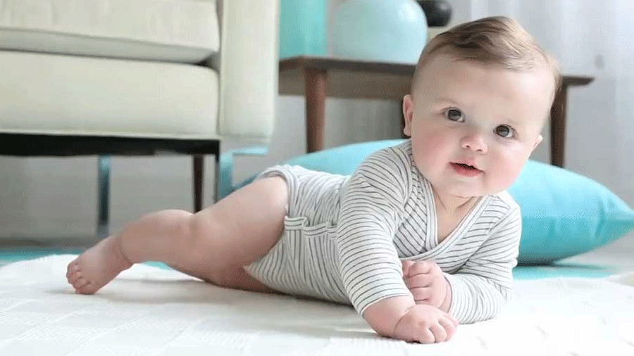 Bayi sedang meniarap di atas tilam melakukan aktiviti tummy time.