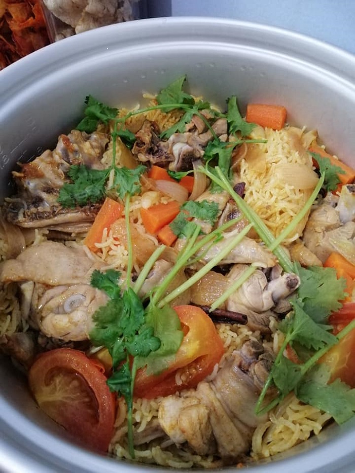 Sepinggan nasi briyani maghribi berwarna kekuningan dengan ayam, tomato, carrot, dan daun ketumbar.