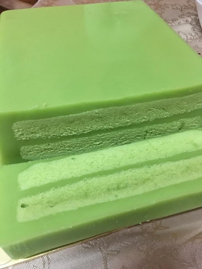 Kek pandan layer hijau yang dipotong menampakkan lapisan krim kastard di tengahnya.