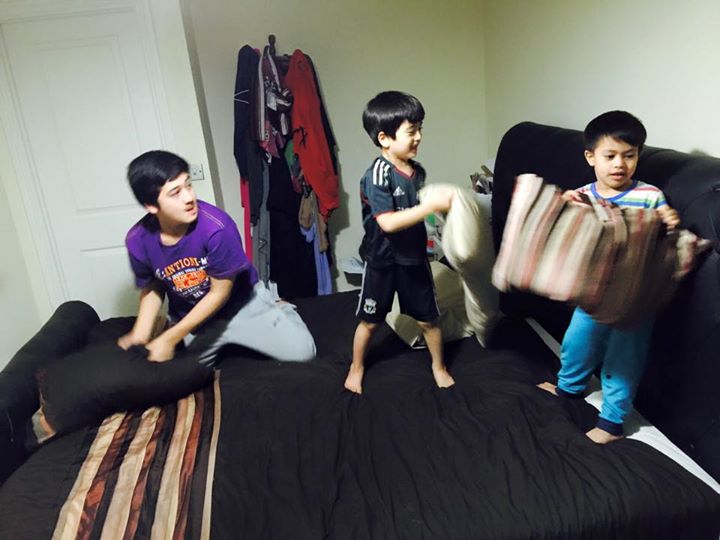 Gambar tiga beradik sedang bermain gembira di dalam rumah semasa cuti sekolah.