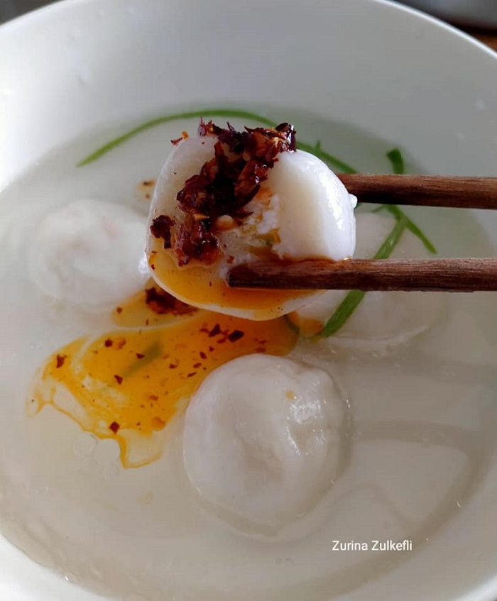 Sebiji bebola ayam tepung pulut yang sudah masak di dalam mangkuk sup, kelihatan seperti dumpling.