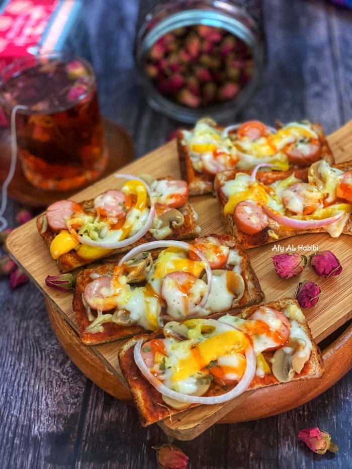 Roti pizza cheezy extra yang dipanggang menggunakan pan dengan topping sosej, cendawan dan keju mozarella yang mencair.