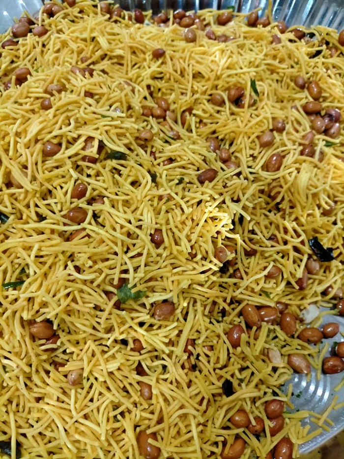 Snek Omapodi rangup dalam bekas kuning keemasan, snek tradisional India untuk perayaan.