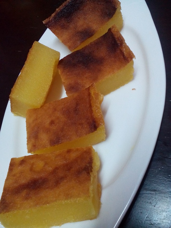 Potongan kuih bingka ubi kayu tradisional yang kekuningan dan ber tekstur padat.