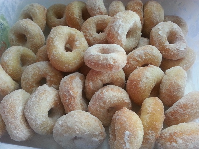 Imej donat gebu berwarna keemasan tersusun dalam bakul, bersalut gula aising.