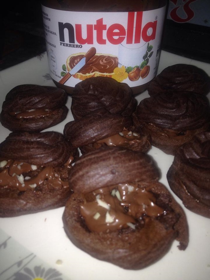 Gambar cream puff coklat yang telah siap dipaip dengan krim ganache dan ditabur badam.