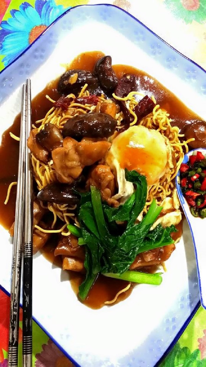 Gambar sizzling yee mee dengan kuah, ayam, cendawan dan sayur sawi di atas pinggan