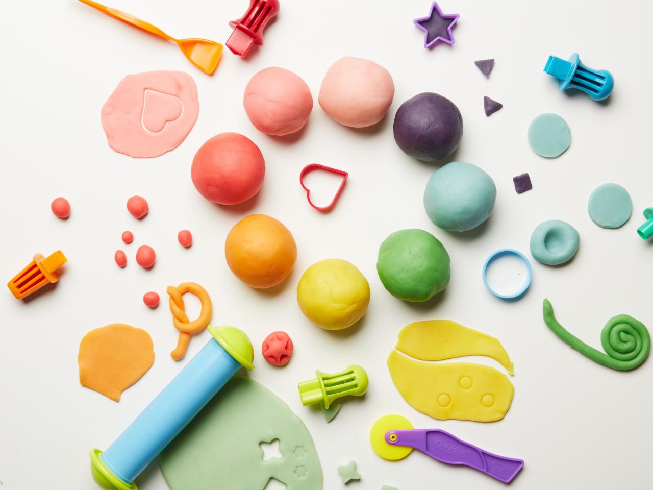 Guru wanita memegang huruf 'playdough' sebagai panduan aktiviti pra-penulisan kanak-kanak.