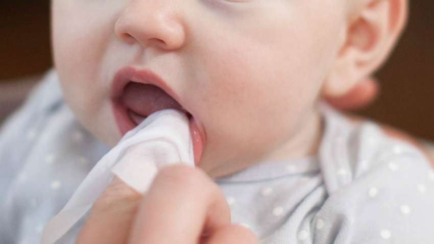 Ibu membersihkan gusi dan bahagian dalam mulut bayi