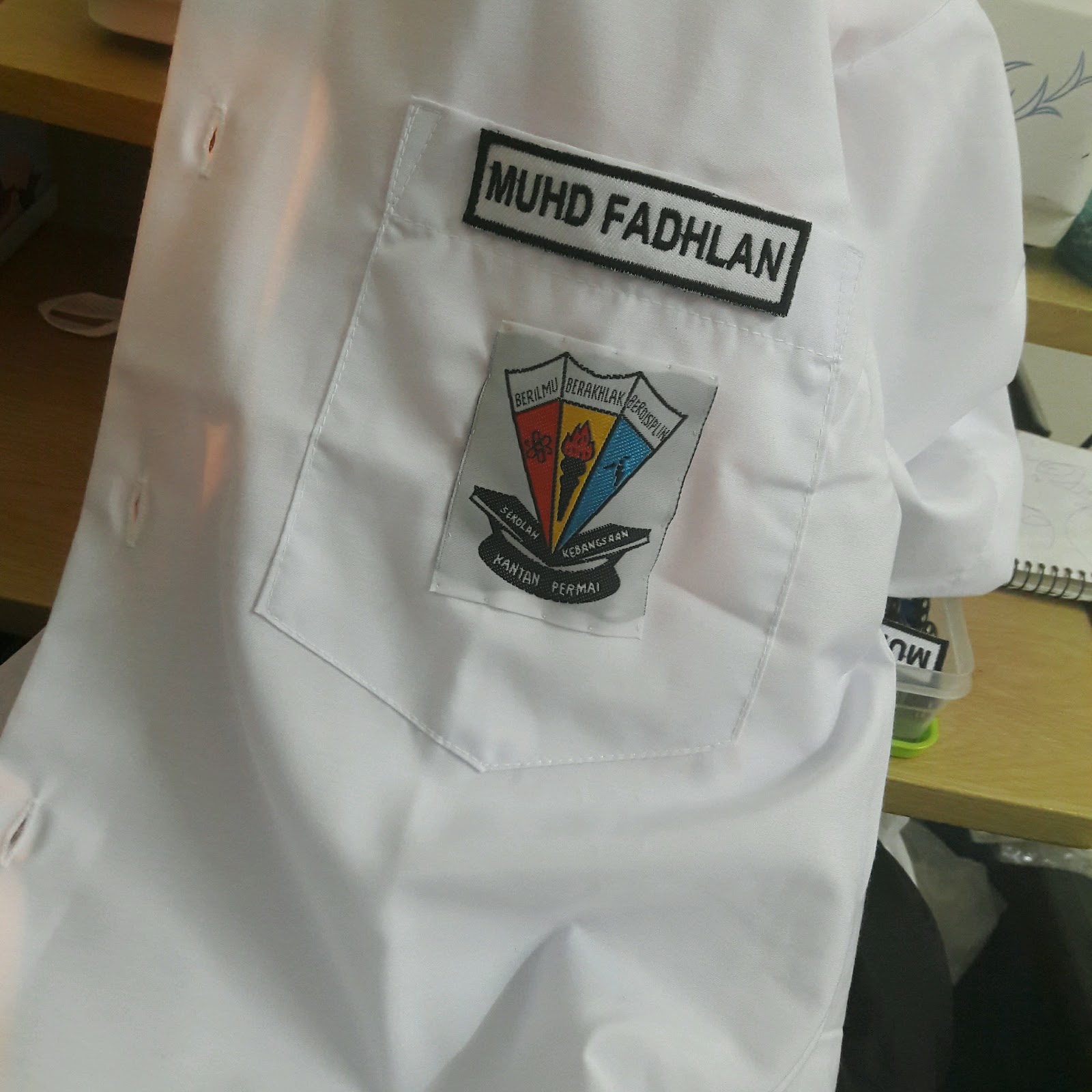 Lencana sekolah diletakkan atas baju seragam sekolah untuk ditampal