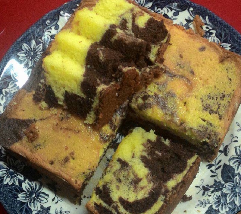 Sekeping kek marble yang telah siap dibakar dan dipotong menunjukkan corak campuran adunan coklat dan asal.