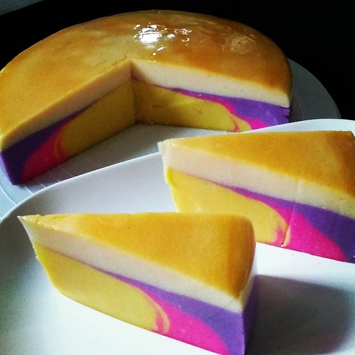 Puding roti berkaramel berlapis warna warni yang dipotong dan diletakkan di atas pinggan rata.