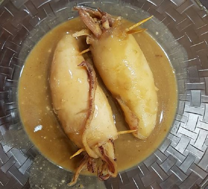 Ketupat sotong berisi pulut yang dimasak dalam kuah santan pekat berwarna coklat keemasan.