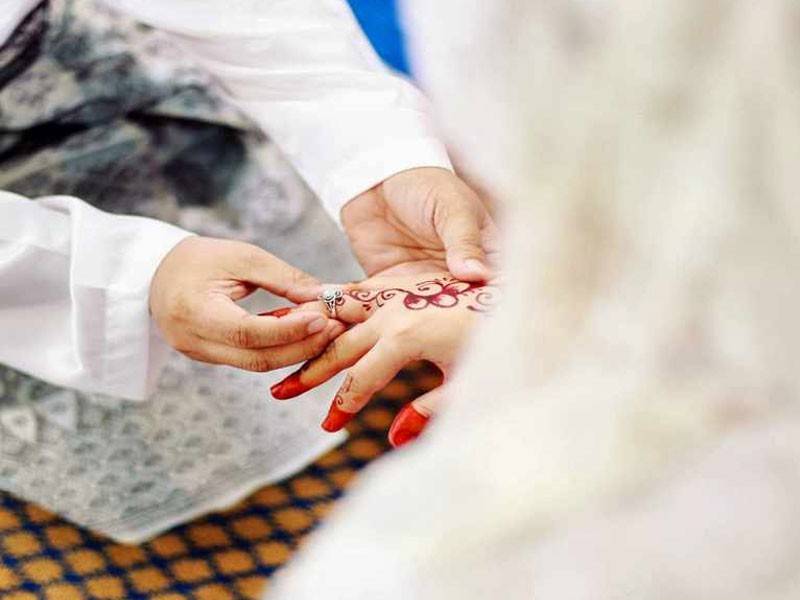 Gambar pasangan pengantin muslim sedang bergurau senda sebagai lambang kebahagiaan rumahtangga.