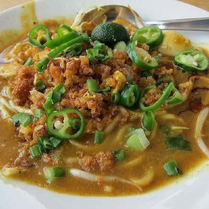 Sebuah hidangan Mi Rebus Johor dengan mee kuning, kuah pekat, taugeh, tauhu goreng dan hiasan lain di dalam mangkuk.