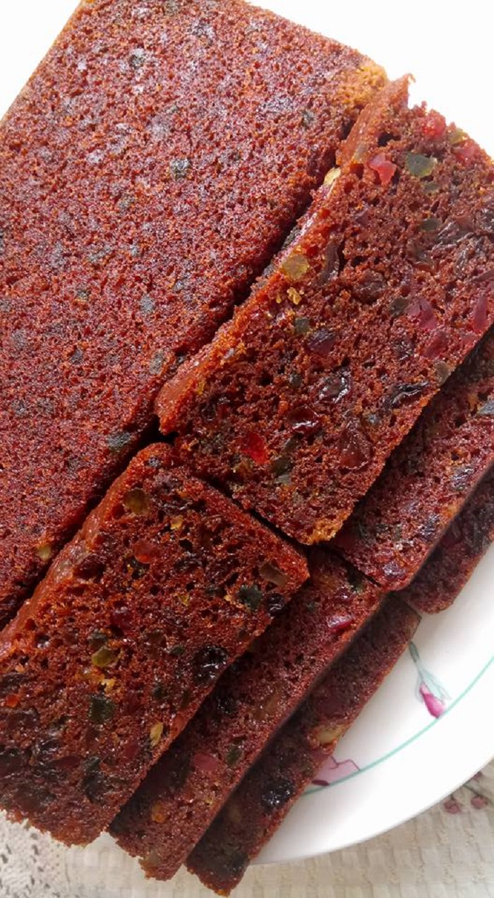Potongan kek buah kukus super moist berwarna coklat keperangan dengan campuran buah-buahan.
