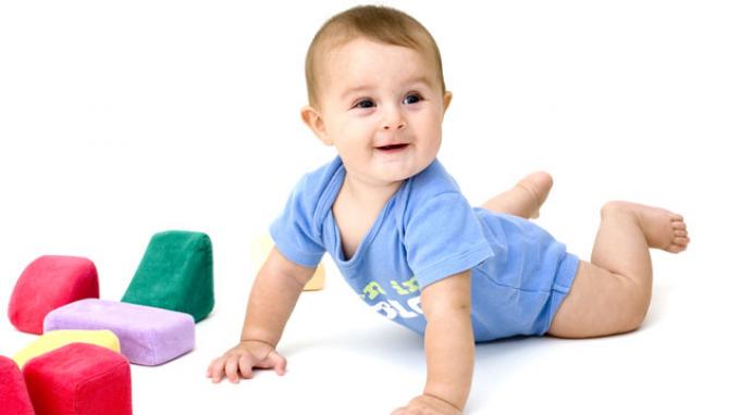 Gambar bayi sedang merangkak di atas lantai sambil bermain dengan mainan.