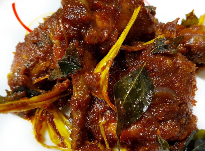 Hidangan ayam masak bali yang kelihatan pedas dan merah.
