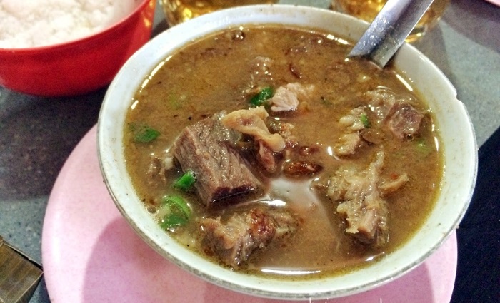 Penjual Coto Makassar sedang menyediakan soto daging di gerai