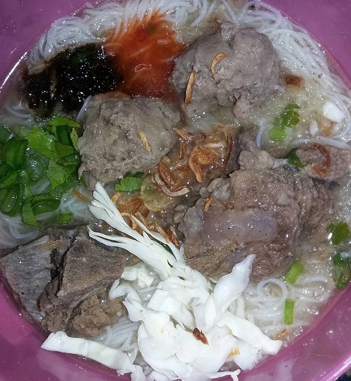 Semangkuk bebola daging kuah mihun dengan hiasan daun dan bawang goreng