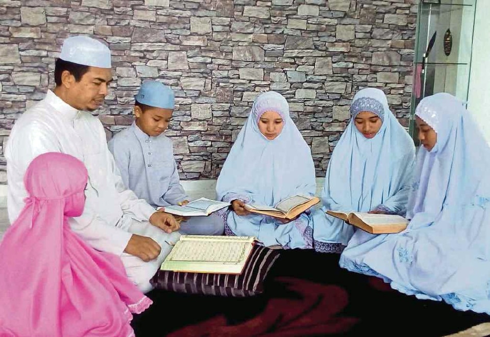 Keluarga bahagia duduk bersama melambangkan peranan ibu bapa dalam kehidupan.