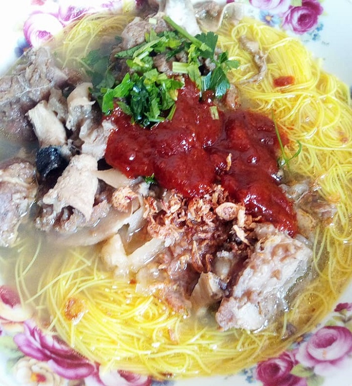 Sebuah mangkuk berisi bihun sup utara dengan kuah daging dan taburan daun sup.