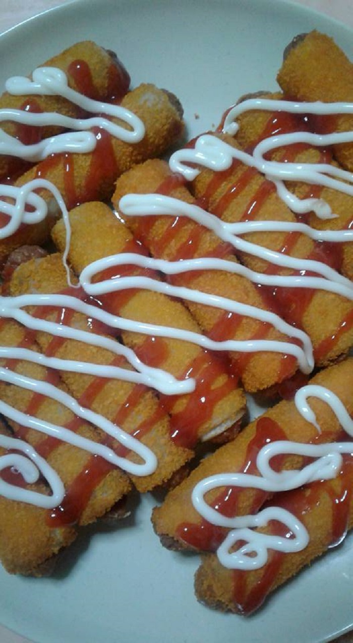 Roti sosej yang telah siap digoreng dengan warna keemasan disusun di atas pinggan.