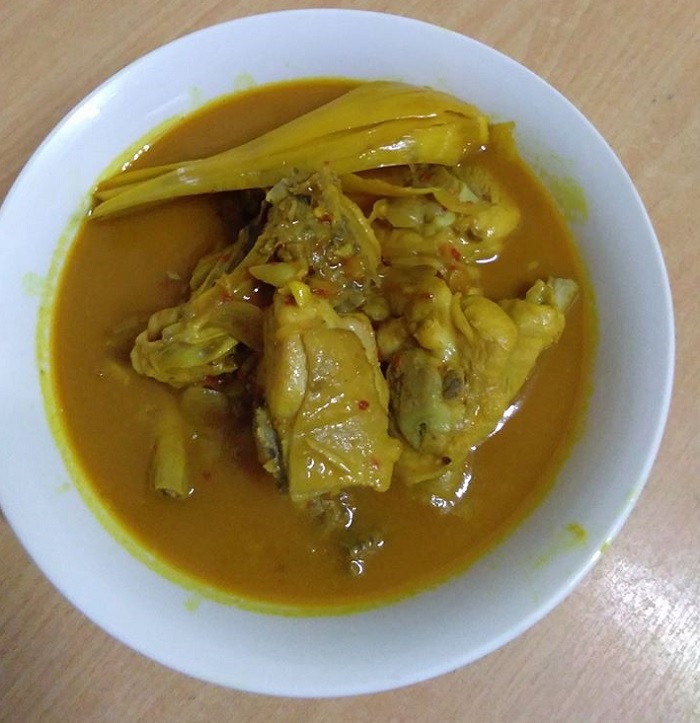 Gambar hidangan ayam masak kunyit dengan kuah pekat kuning keemasan.