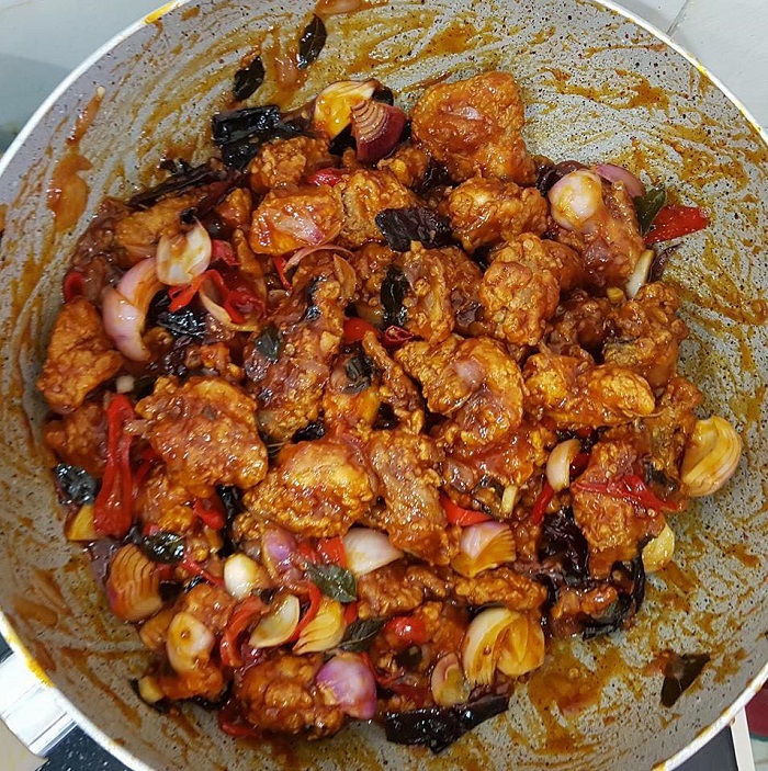 Hidangan ayam masak cili kering ala Cina Muslim dengan hirisan cili dan bawang.