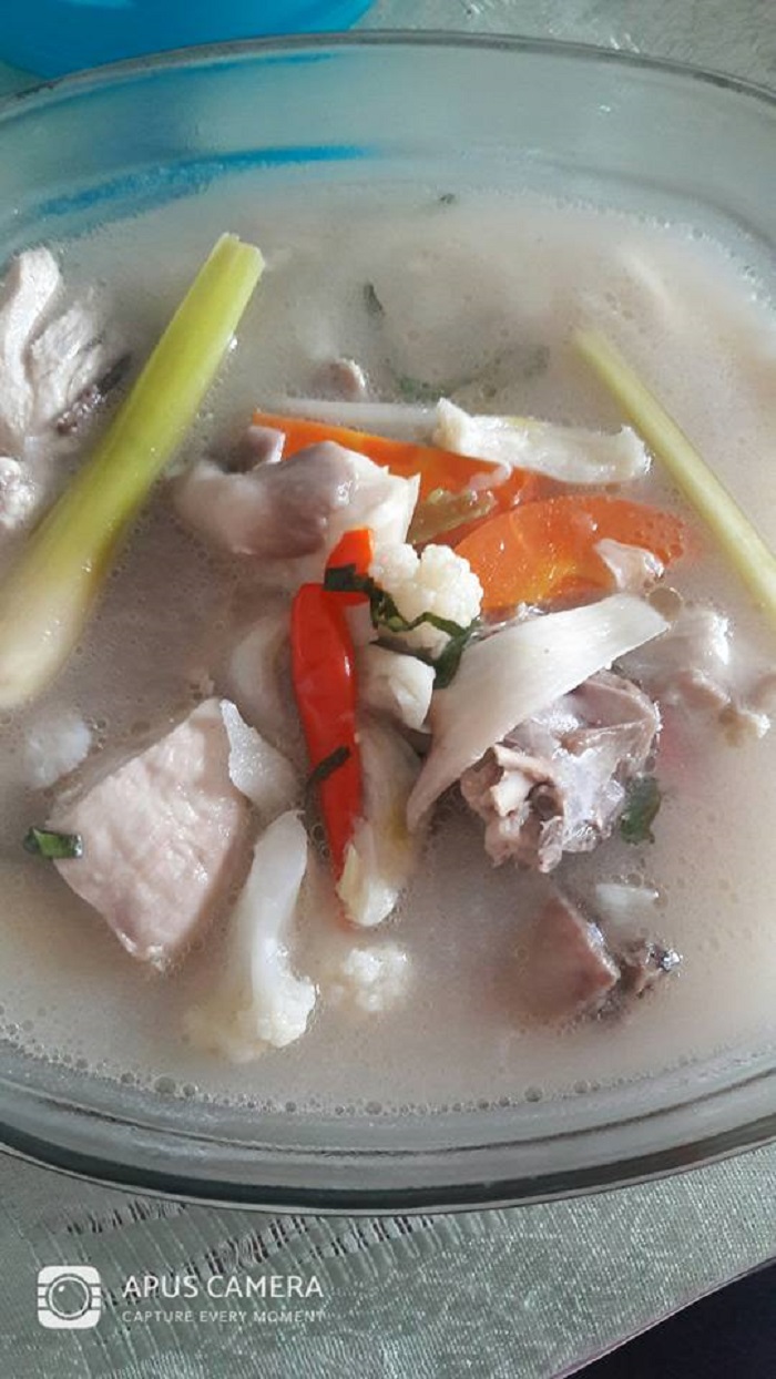 Sebuah mangkuk berisi sup tomyam putih dengan ayam, cendawan dan sayur-sayuran.