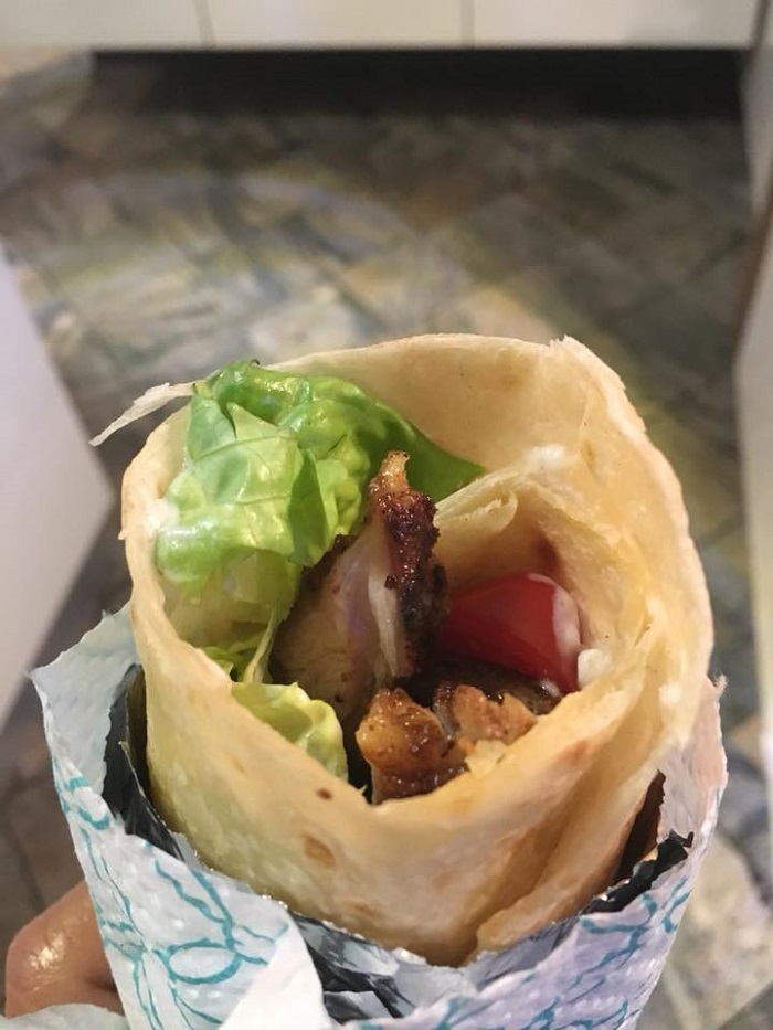 Gambar shawarma ayam di atas pinggan, dihiris nipis dengan sayuran segar dan roti arab.