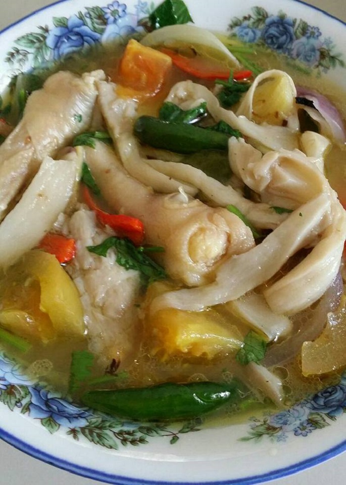 Sebuah mangkuk berisi sup kaki ayam ala Thai yang sedap dengan hirisan daun ketumbar.