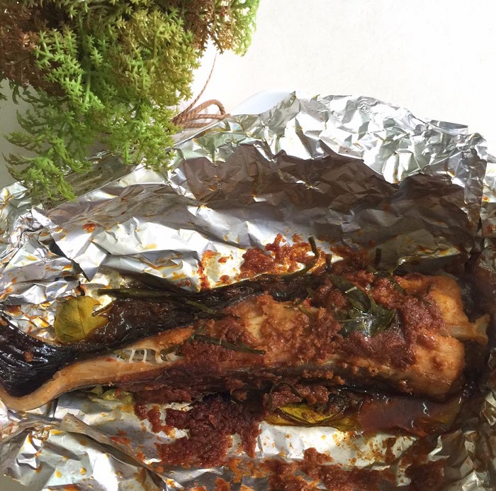 Ikan pari bakar bersambal di atas daun pisang dengan taburan daun limau purut