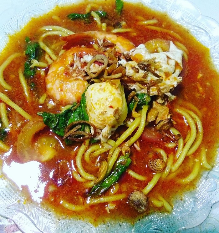 Semingkuk mee bandung dengan kuah pekat, udang, sayur sawi dan taburan bawang goreng dalam mangkuk.
