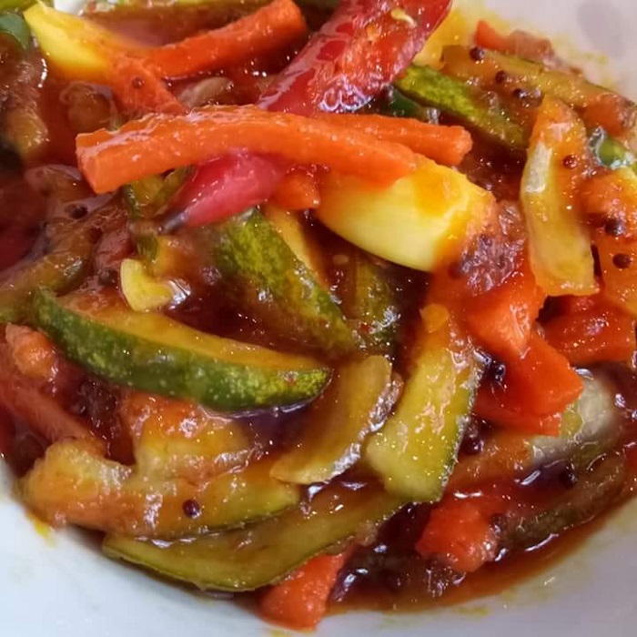 Mangkuk berisi acar timun dan lobak merah yang dipotong memanjang bersama cili dan bawang kecil.