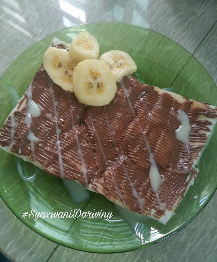 Pancake pisang Thai yang digoreng menggunakan kulit popia dengan topping coklat dan susu pekat.