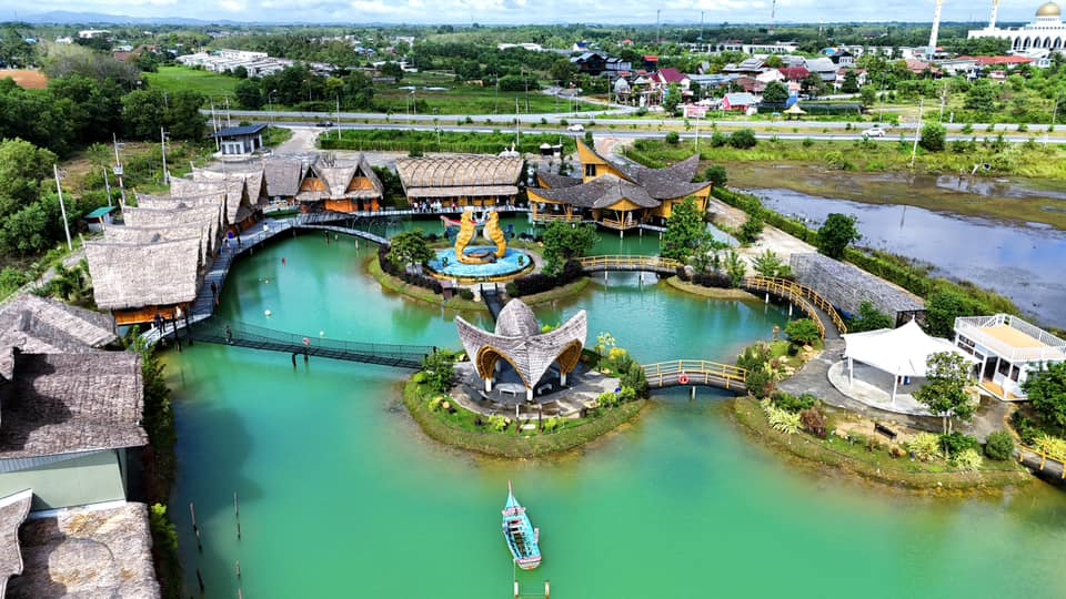 Pemandangan bandar Hatyai Thailand dengan elemen ikonik patung duyung dan menara dalam latar belakang ceria.