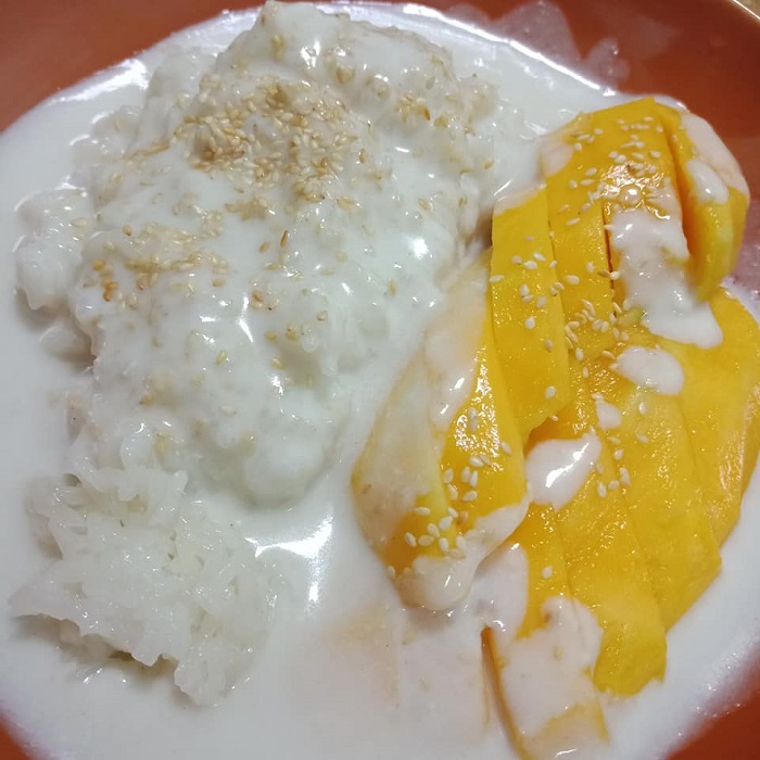 Sepinggan hidangan pulut mangga Thai dengan nasi pulut putih, hirisan mangga dan kuah santan ditabur bijan.