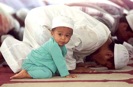 Kanak-kanak lelaki sedang bersolat berjemaah di dalam masjid.