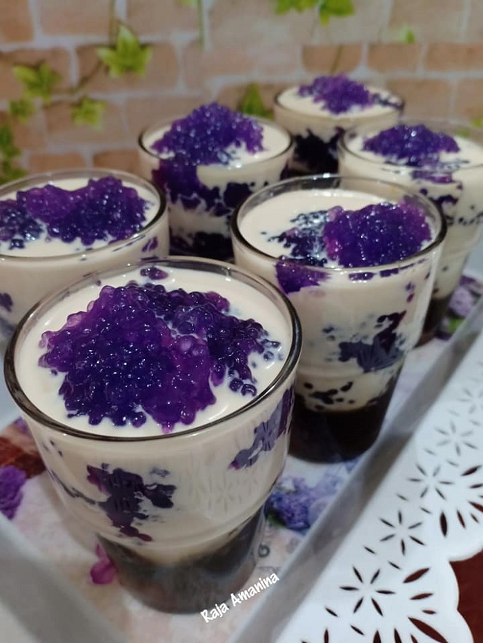 Puding sagu gula melaka berwarna ungu dihidangkan bersama susu cair dan sirap gula melaka.