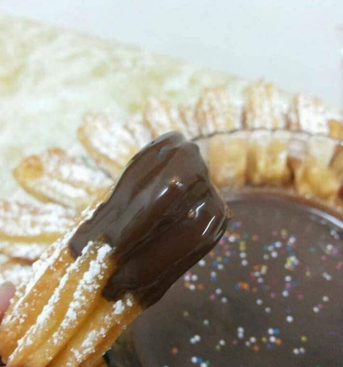 Imej churros yang digoreng keemasan disiram sos coklat meleleh