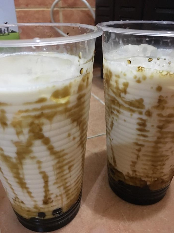 Gelas minuman boba drink bersusu berkaramel dengan topping boba hitam.