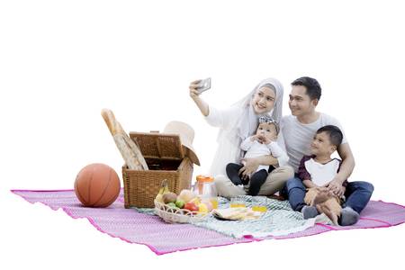 Keluarga Muslim mengambil gambar sambil berkelah