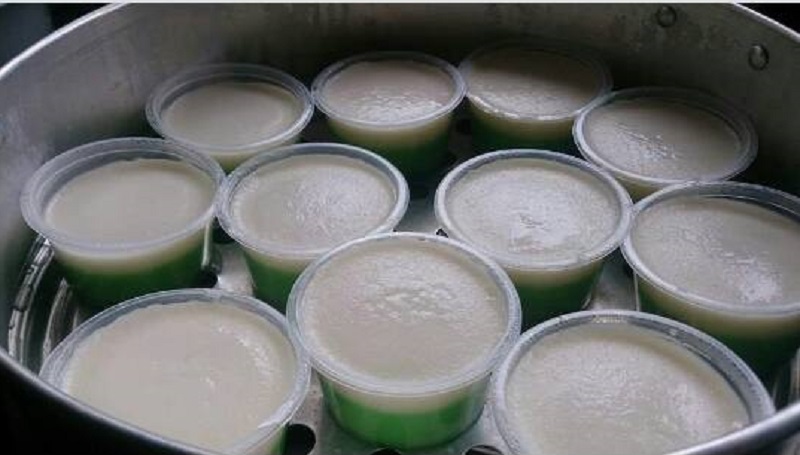 Imej kuih tepung pelita berlapis warna hijau dan putih di dalam bekas kecil.