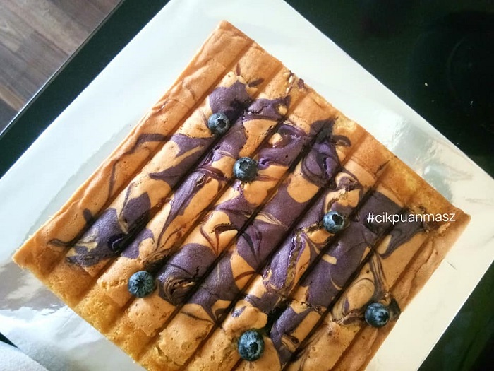 Kek butter blueberry yang dibakar dengan hiasan inti blueberry di atas permukaan.