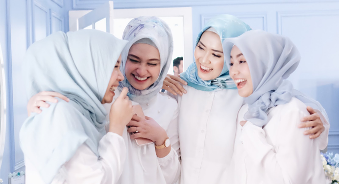 Dua orang kanak-kanak perempuan sedang duduk bersama sambil tersenyum melambangkan persahabatan yang baik.