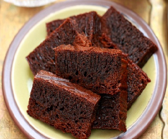 Kek gula hangus kukus berwarna hitam keemasan dengan tekstur sarang semut dihiris dalam pinggan