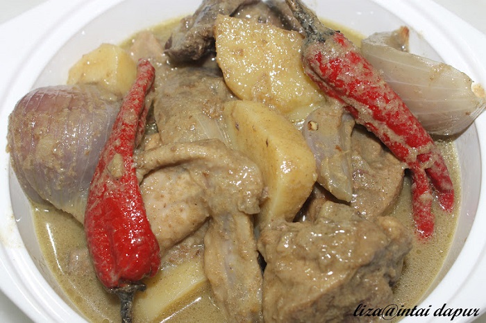Hidangan ayam masak kurma pekat dengan rempah dan kentang di dalam pinggan.