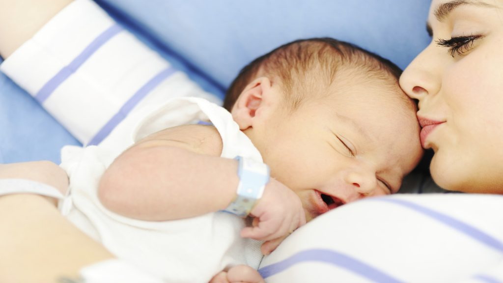 Ibu sedang mencium bayi yang baru dilahirkan